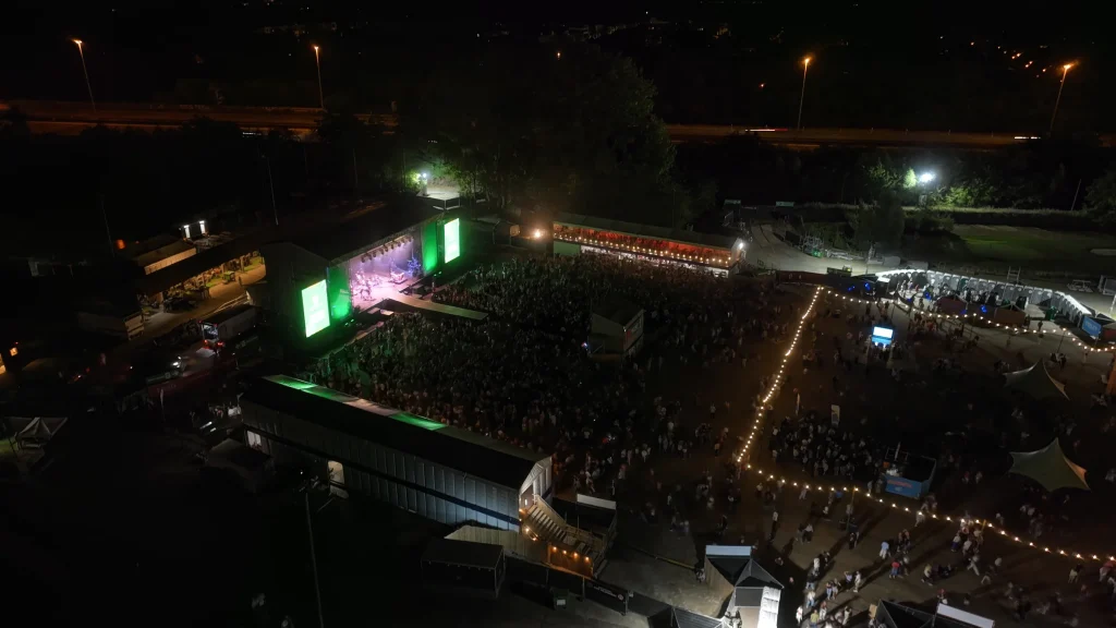 Fairway Festival at night from the air: stage, crowd and string lights at the golf club