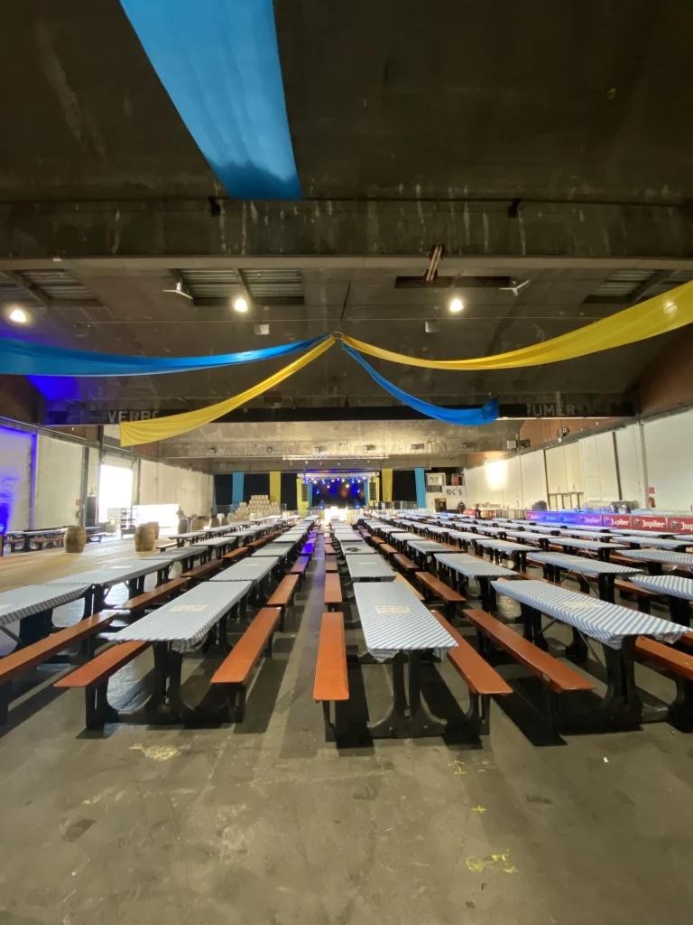 Feesthal met lange biertafels en blauw-gele doeken vóór de opening van Oktoberfest