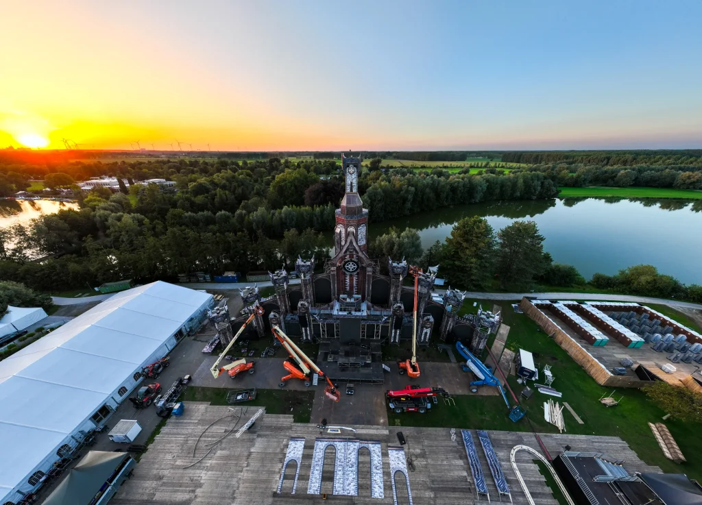 Mainstage van The Qontinent 2023 in opbouw met hoogwerkers, luchtbeeld bij zonsondergang
