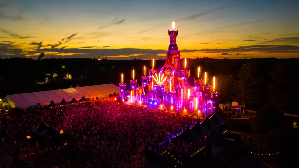 Mainstage van The Qontinent 2023 met vlammen en publiek bij avond, luchtbeeld