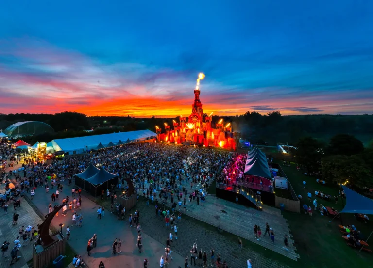Aerial of The Qontinent 2023: illuminated main stage and crowd at sunset