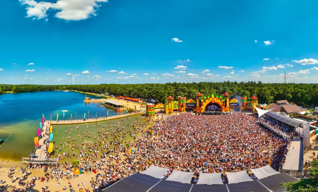 Panoramisch luchtbeeld van het strand, het meer en de mainstage van Sunrise Festival 2025