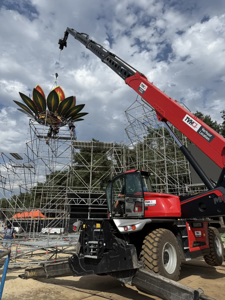 Verreiker plaatst een decorbloem op de stage van Sunrise Festival 2025