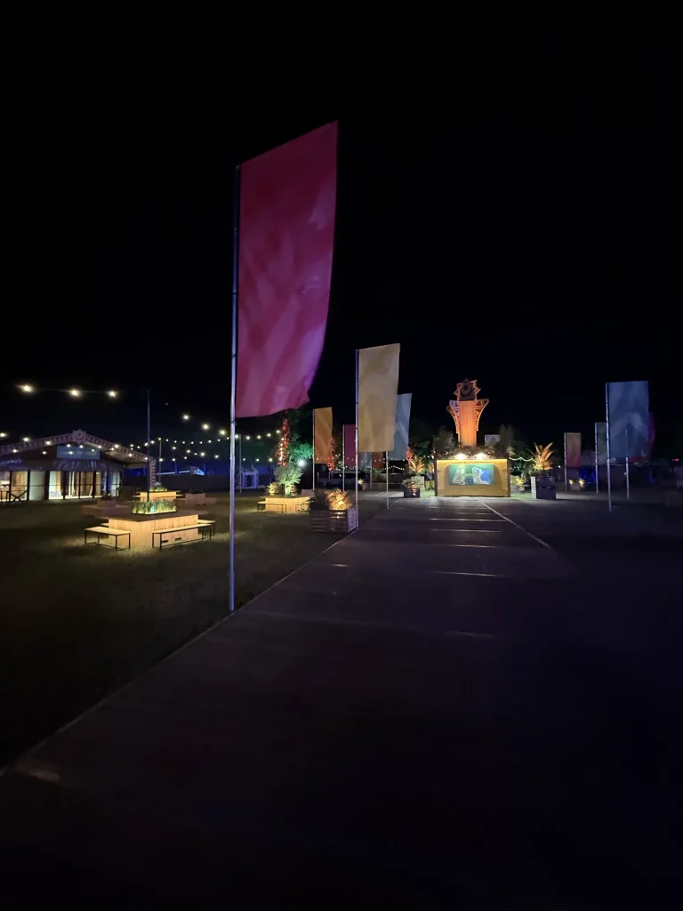 Verlichte festivalstraat met vlaggen bij nacht op Sunrise Festival 2025