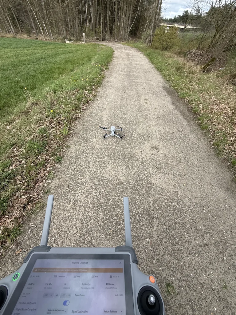 Mappingdrone klaar voor vertrek op een bospad, met controller in de hand