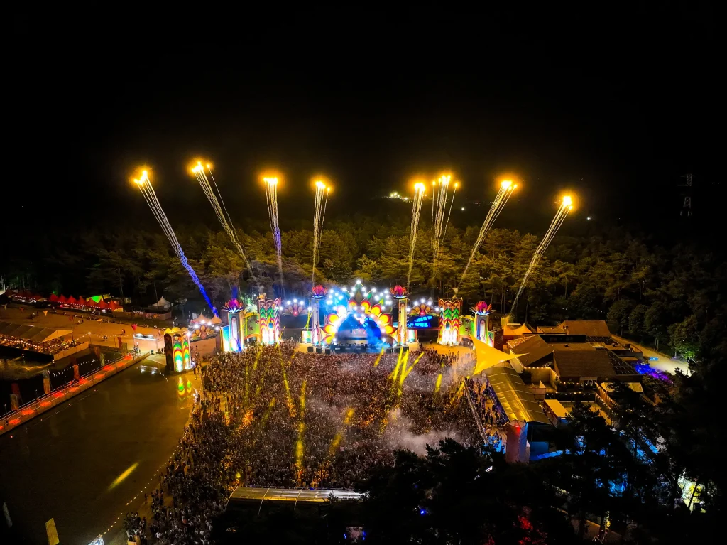 Vuurwerkstralen boven de verlichte mainstage van Sunrise bij nacht, luchtbeeld