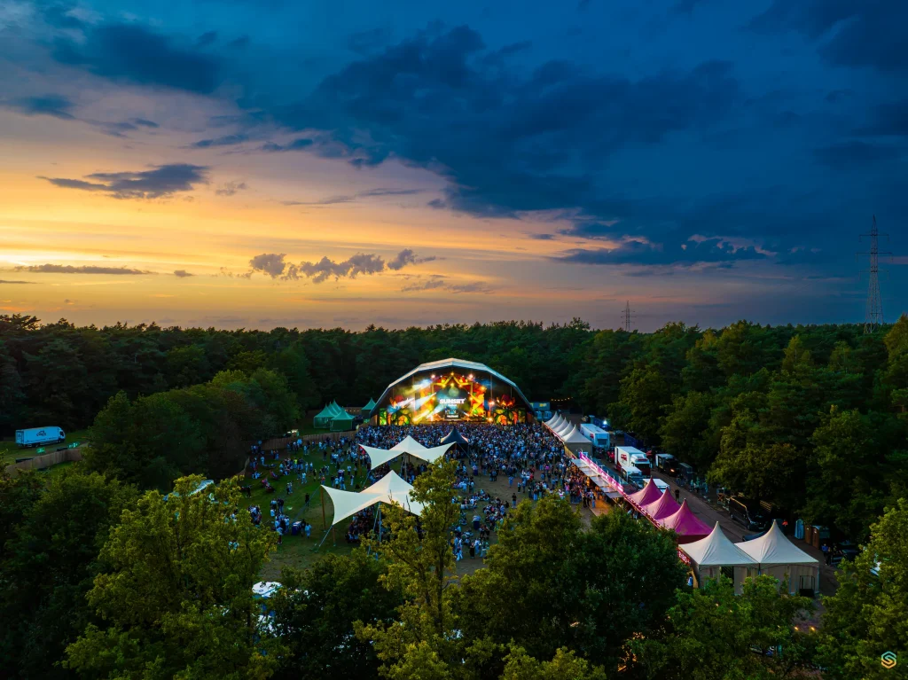 Illuminated main stage and bar zone of Sunset Festival 2025 at dusk, aerial