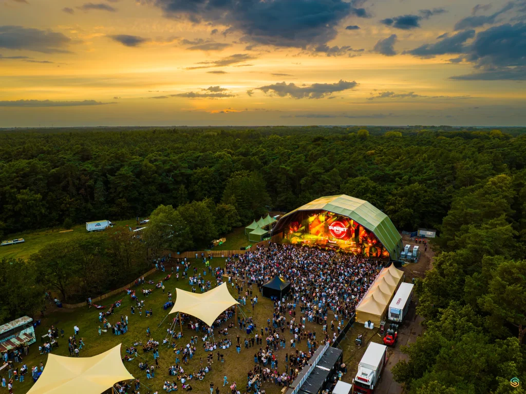 Aerial of Sunset Festival 2025 at sunset: main stage and crowd in the De Lilse Bergen woods