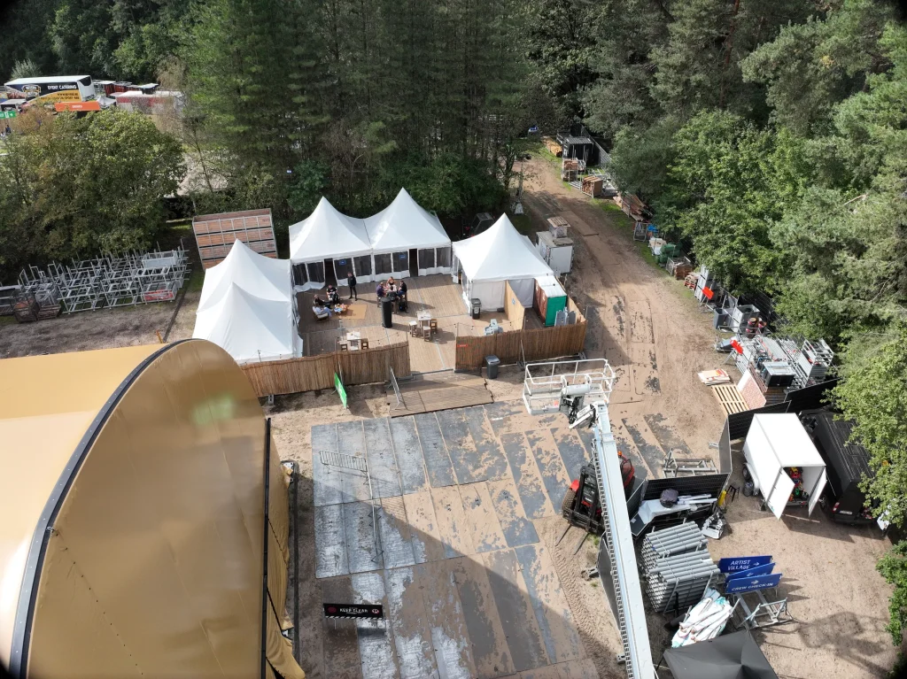 Backstagezone met tenten en containers naast de hal, luchtbeeld