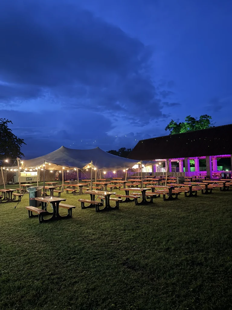Verlichte terrastent met picknicktafels bij nacht op Vagebond Weekend 2026